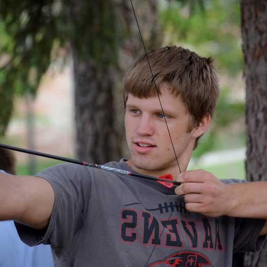 A student draws an arrow back in a bow in Engineering class